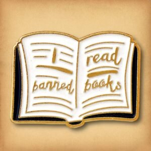 Aesthetic book lover enamel pin with "I read banned books" gold lettering on white pages.