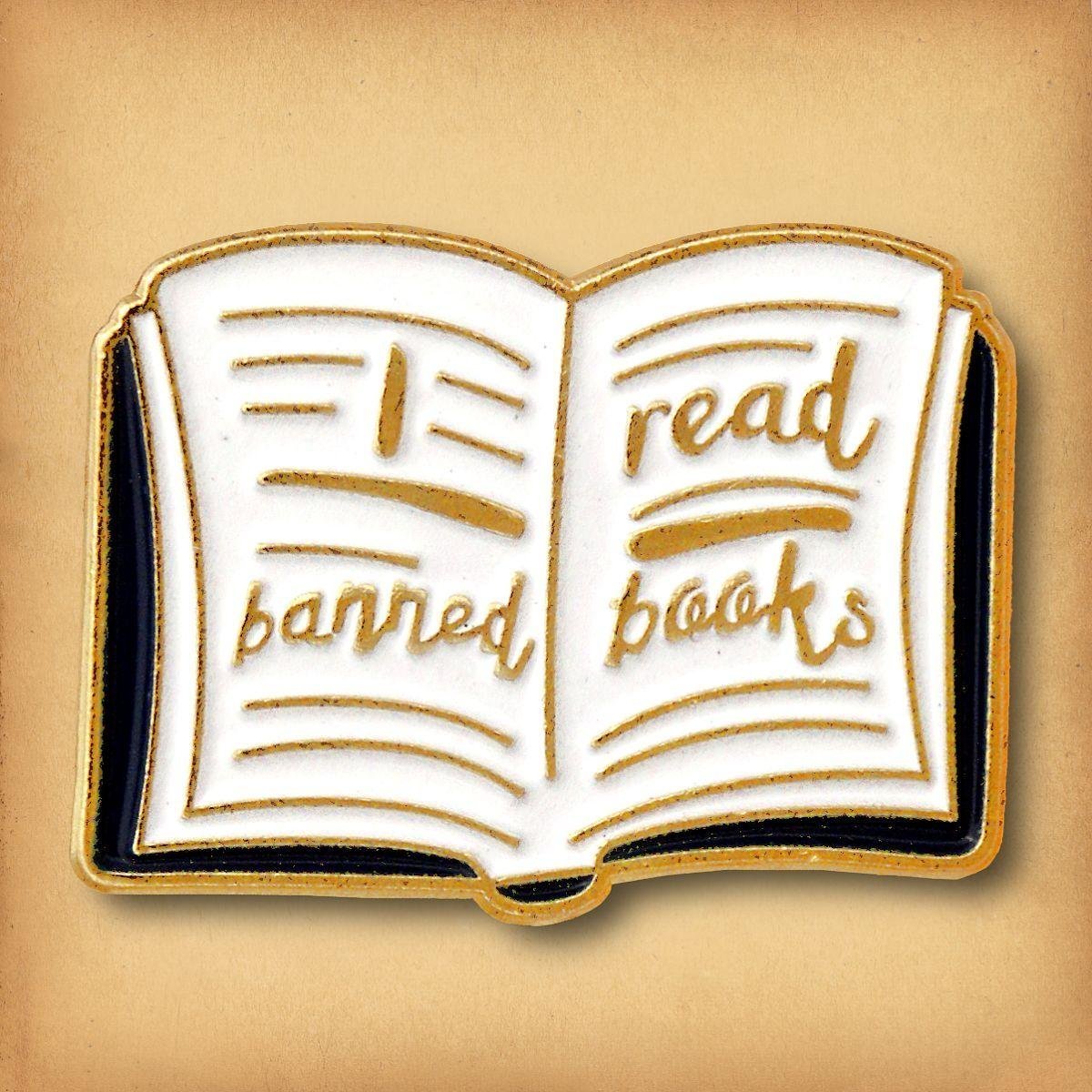 Aesthetic book lover enamel pin with "I read banned books" gold lettering on white pages.