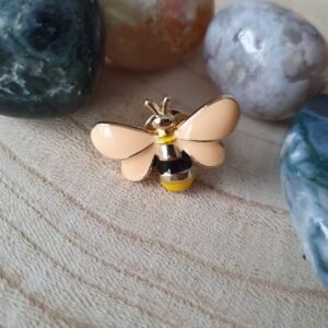 Honey bee enamel pin with gold plating and peach wings.