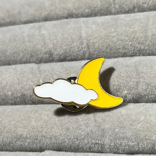 Crescent moon and cloud enamel pin with gold plating and vibrant yellow and white colors.