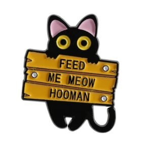 Hungry black cat enamel pin with a yellow sign saying Feed Me Meow Hooman.