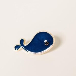 Nautical navy blue whale enamel pin with polished gold plating and a minimalist white and black eye.