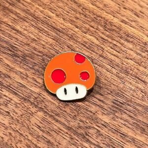 Orange mushroom enamel pin inspired by retro video games.