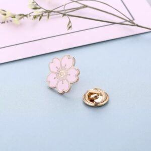 Dainty pastel pink cherry blossom enamel pin with five petals and detailed gold-toned stamen at the center.