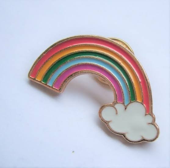 Rainbow enamel pin on a denim jacket for a retro aesthetic.