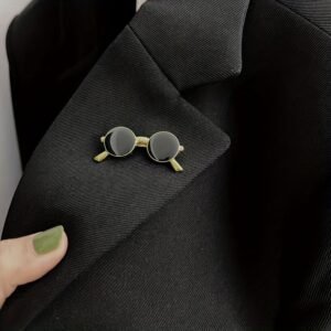Sunglasses enamel pin attached to a dark suit jacket lapel for a professional yet trendy look.
