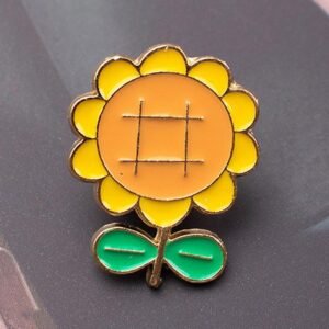 Sunflower enamel pin with yellow petals and a metallic grid center.
