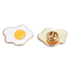 Enamel pin of a fried egg with a bright yellow yolk, shown alongside its gold-textured back and clutch.