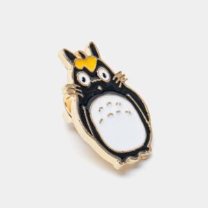 Enamel pin of a grey and white forest spirit character with large eyes and a yellow crown detail.