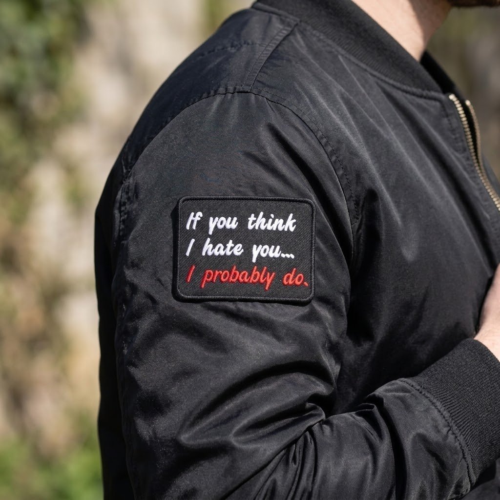 Targhetta con la scritta “If You Think I Hate You” sulla manica di un bomber nero